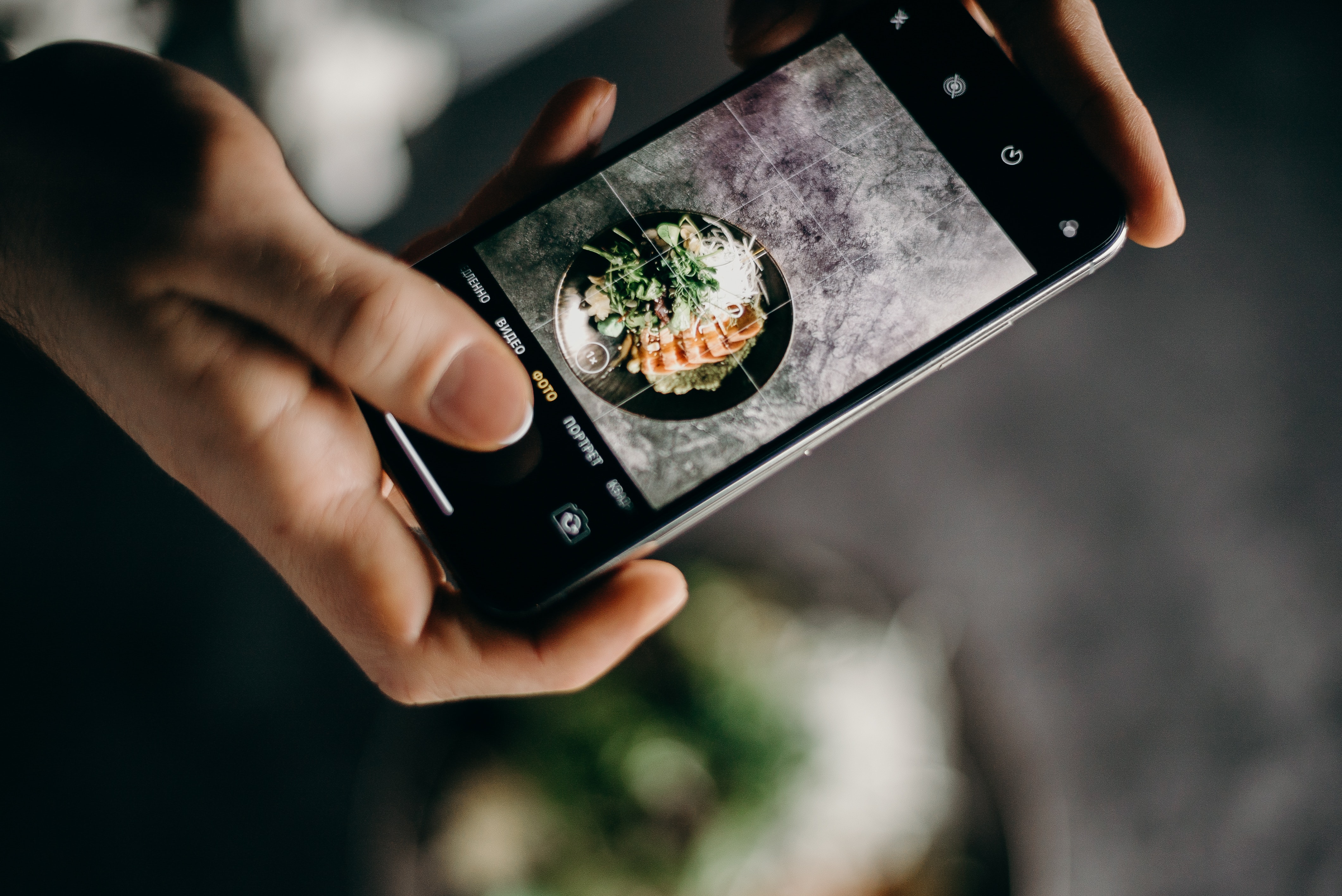 Someone taking a photo of a ramen dish using their phone